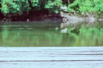 Empty wooden plank terrace over green river and forest background - nature product / advertise display concept