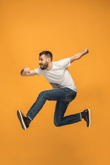 Freedom in moving. handsome young man jumping against orange background