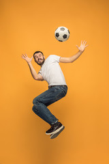 The young man as soccer football player kicking the ball at studio