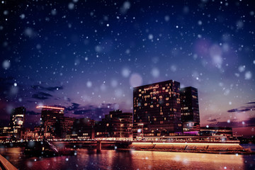 Fototapeta premium Panorama of the night city of Dusseldorf in winter during a snowstorm. Bokeh light effect, soft filter