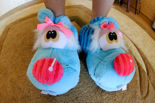 Soft Blue Home Slippers In The Form Of A Plush Toy On The Female Legs.