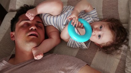 Young tired father sleep near a little child in a bed