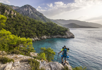 Fototapeta premium tourist with backpack standing on a cliff in mountains near mediterranean sea