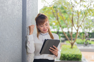 Fototapeta premium Elegant modern business woman working on tablet screen in an urban environment
