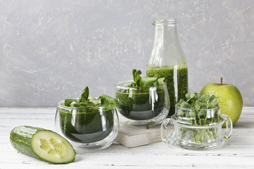 Close up of homemade green smoothie made from fresh spinach, peas, cucumber and apple on white wooden background