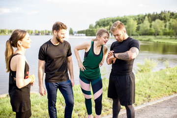 Sports team having fun standing together after the training outdors in the park near the lake