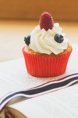 Cupcake with raspberry and blueberry, soft focus background