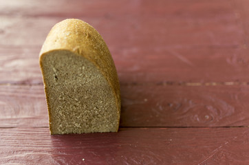 A piece of a loaf of black bread with a bitten crust.