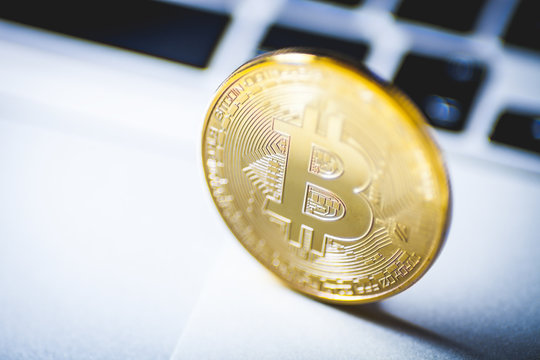 Bitcoin coin close up with laptop in background, cryptocurrency concept