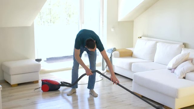 household and cleaning concept - man with vacuum cleaner at home