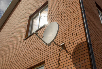 satellite dish dish on the wall of a red brick cottage