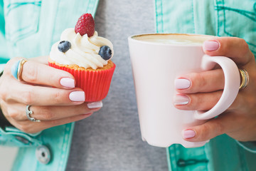 Woman with a cup of cappuccino and a piece of dessert on the plate, soft focus background