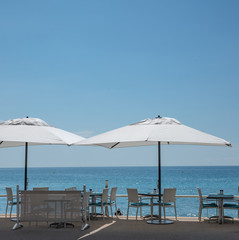 Fototapeta na wymiar Menton, France Unbrellas and tables by the sea