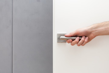 The man opens white door with metallic handle