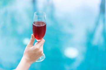 hand holding red wine glass in pool