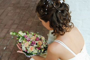 Beautiful wedding bouquet in the bride's hands. The bride is squatting and holding a bouquet. Wedding day.
