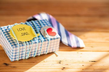 Happy fathers day concept. colorful tie and gift box with LOVE DAD tag on wooden table background.