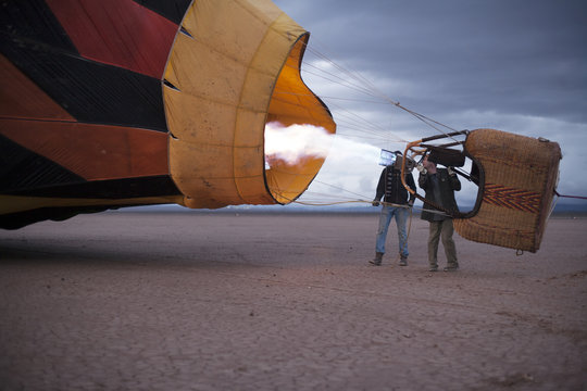 Fototapeta Two men flying a hot air balloon in a dry lake bed