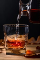  Whiskey is poured into a glass from a carafe.