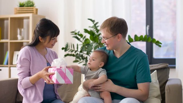 family, parenthood and mothers day concept - happy mother receiving gift box from father and baby boy at home