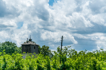 Old wooden prison watchtower in work camp built during the world war two with trees and blue sky with clouds