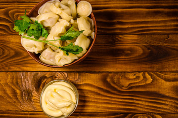 Fresh dumplings in ceramic bowl on wooden table. Top view