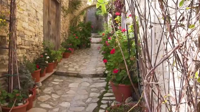 Lefkara street with flowering plants and stone arch, Cyprus 