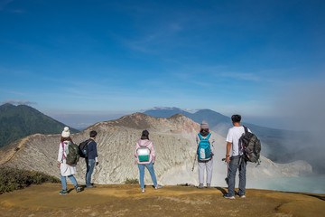Group of tourists who are standing views on crater Kawah Ijen, Indonesia.