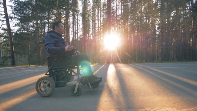 Disabled person rides in a wheelchair on the road.