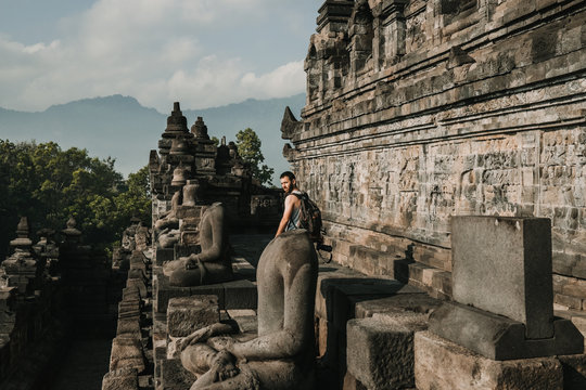 Handsome young tourist feeling the peace of the great Borobudur temple, historical famous place in the java island Indonesia. Lifestyle and travel photography.