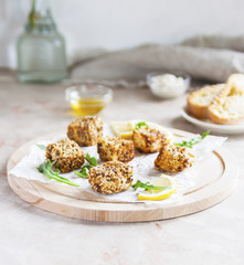 Cheese, diced and fried in batter and sesame on a wooden Board. White background.
