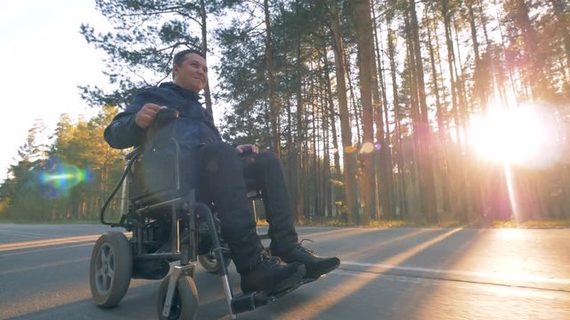 A man in wheelchair takes a ride on a forest road.