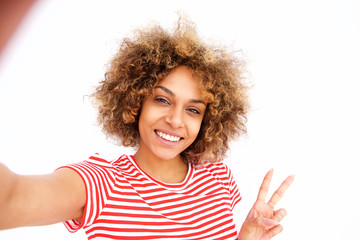 Naklejka premium Portrait of beautiful young african american woman taking selfie against white wall