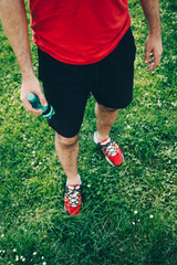 Fototapeta na wymiar Close-up of man wearing running shoes and holding a water bottle