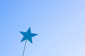 blue metal star on a stick against the sky