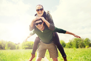 Fototapeta premium travel, hiking, backpacking, tourism and people concept - happy couple with backpacks having fun and walking along country road outdoors