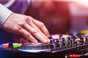 closeup hands of disk jockey at the dj controller wearing in white shirt at night club. EDM, party clubbing life concept