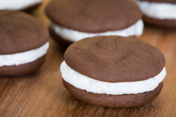 Whoopie pies or moon pies, chocolate cake desserts filled with creamy frosting against wooden background