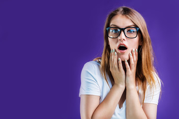 Portrait of pretty blonde woman dressed in white t-shirt and eyeglasses posing with excited face expression, isolated on blue studio background