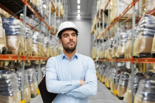 logistic business, shipment and people concept - businessman in helmet at warehouse