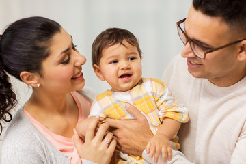 family, parenthood and people concept - happy mother, father with baby daughter at home