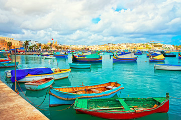 Fototapeta na wymiar Luzzu boats in Marsaxlokk Port embankment bay Mediterranean sea