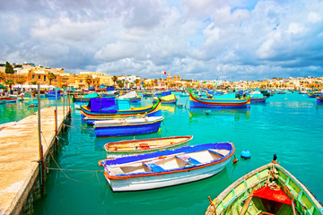 Fototapeta na wymiar Luzzu boats in Marsaxlokk Port embankment of bay Mediterranean sea