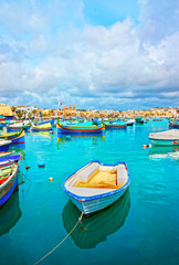 Fototapeta na wymiar Luzzu boats in Marsaxlokk harbor bay Mediterranean sea Malta