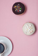 Top view Doughnuts with Chocolate and White Icing and cup of Coffee, on Pastel Pink Background. Sweet Dessert Donuts with Copy Paste.