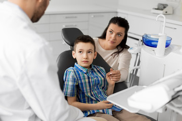 medicine, dentistry and healthcare concept - mother and son visiting dentist at dental clinic
