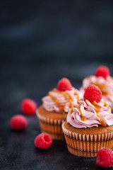 Raspberry and caramel cupcakes on dark background