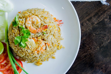 Fried rice with shrimp in a white dish on wood table in thai food style