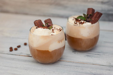 Iced Mocha Frappe Coffee with Whip Cream, Summer Drinking times. Coffee Beans. rustic textured Wooden Background. Mint Leaves