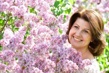 Smiling woman in alilac garden in spring